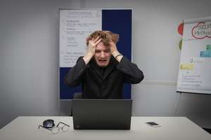 Stressed trader making emotional decisions at computer screen showing Forex charts